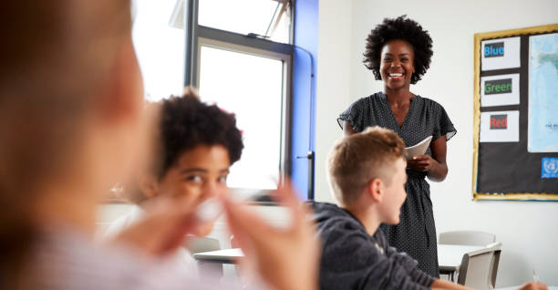 istock Female High School Tutor Standing By Table With Students Teaching Lesson 1047617304
