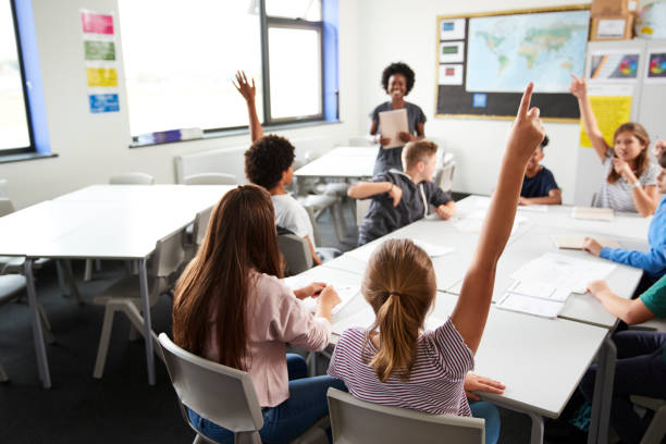 istock High School Students Raising Hands To Answer Question Set By Teacher In Classroom 1047617372