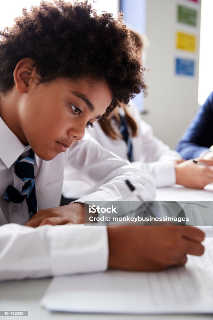 Male High School Student Wearing Uniform Working At Desk School Uniform Stock Photo