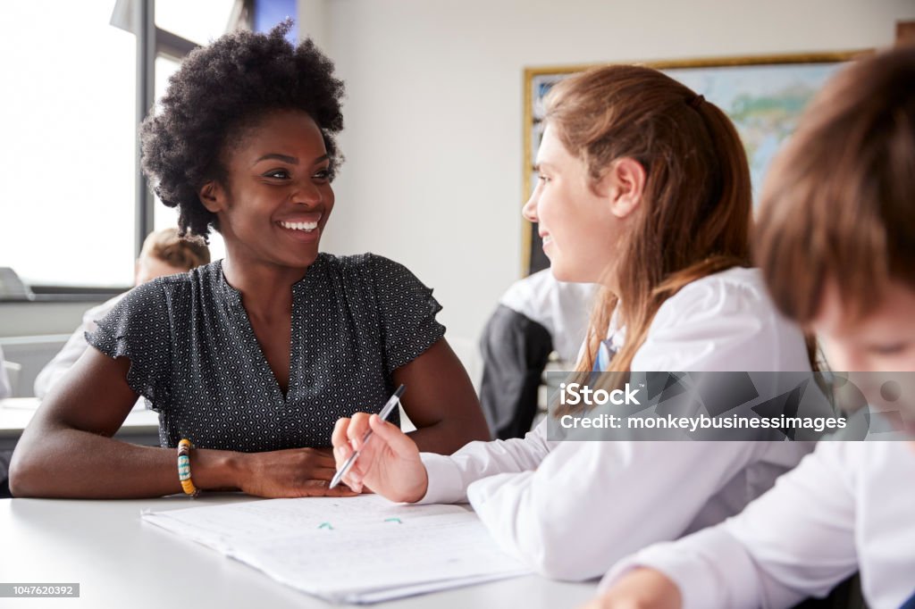 High School Lehrer geben Studentin tragen einheitliche Einzelunterricht am Schreibtisch - Lizenzfrei Lehrkraft Stock-Foto