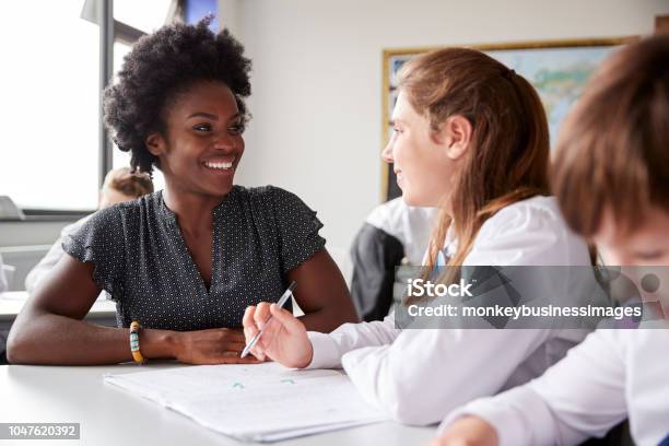 High School Tutor Giving Female Student Wearing Uniform One To One Tuition At Desk Stock Photo - Download Image Now