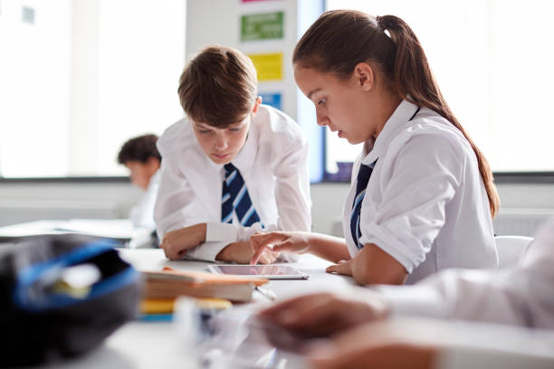 istock Two High School Students Wearing Uniform Working Together At Desk Using Digital Tablet 1047620418