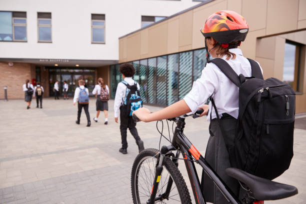 group of high school students wearing uniform arriving at school walking or riding bikes - walk cycle imagens e fotografias de stock