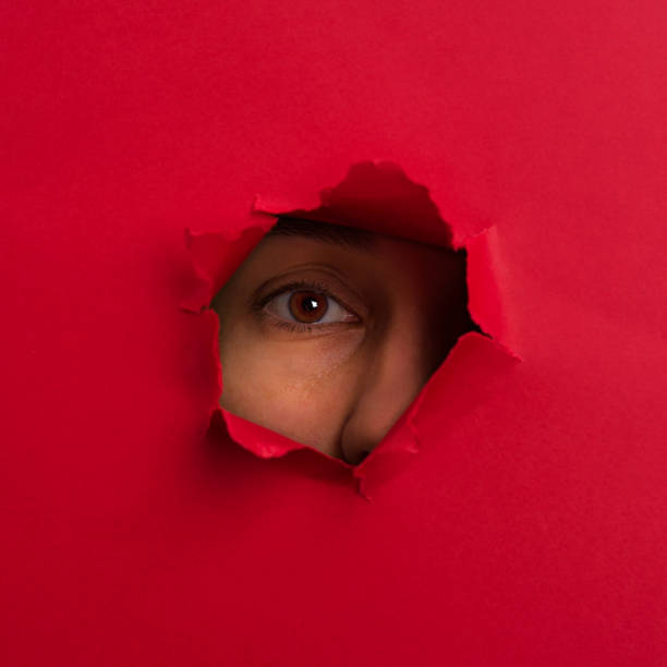 istock Women watches through a hole in cardboard 1047624164