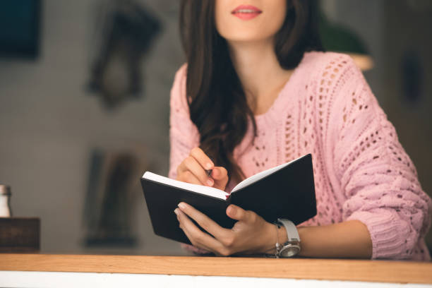 istock partial view of woman making notes in textbook at table in cafe 1047624206