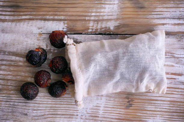 istock Soap nuts spilling from wash bag on wooden background. 1047636488