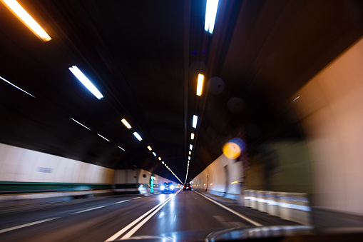 Motion blur POV driving a car at speed through a road tunnel at night