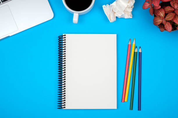 istock Modern blue office desk table with laptop and blank notebook page for input the text. Top view, flat lay 1047640150