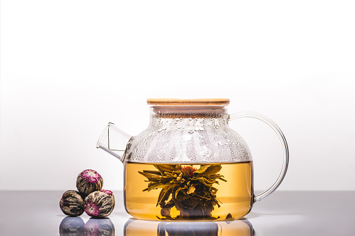 glass teapot of chinese flowering tea with tea balls on table