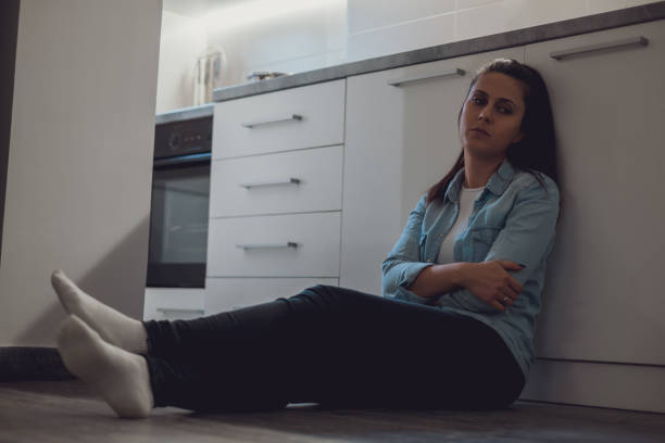 istock Depressed girl sitting on the kitchen floor 1047640596