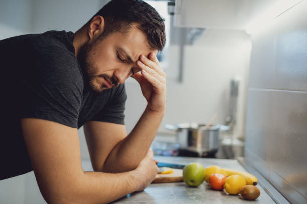istock Man with headache leaning on the kitchen countertop 1047640614