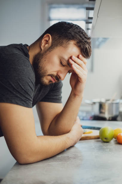 istock Man holding his head and leaning on the kitchen countertop 1047640620
