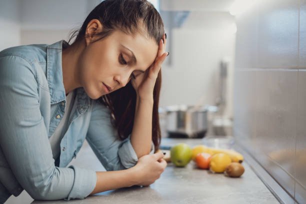istock Sad girl leaning on the kitchen countertop and looking down 1047640622