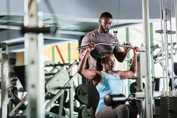 entraîneur personnel aidant la femme d’âge mûr au gymnase - coach exercising instructor gym photos et images de collection