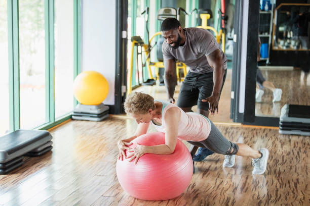 istock Personal trainer helping senior woman at gym 1047643302