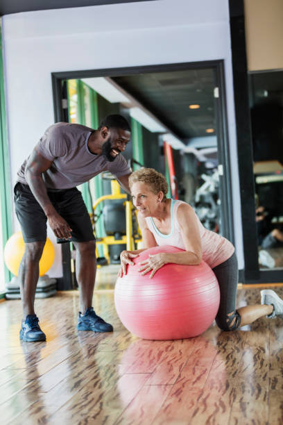istock Personal trainer helping senior woman at gym 1047643552