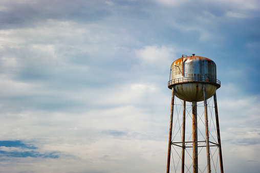 Copy space in a minimalist photography of a rusty water tower under cloudy skies.