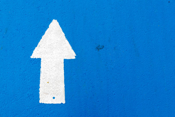 istock White painting in forward direction arrow symbol on blue concrete road background 1047657702