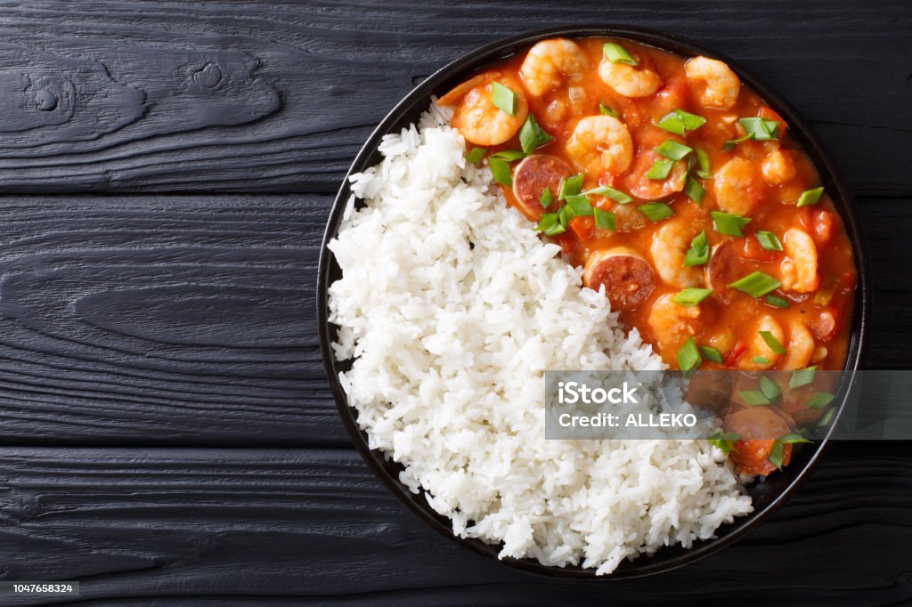 Delicious gumbo with prawns, sausage and rice  on a plate. Horizontal top view Delicious gumbo with prawns, sausage and rice on a plate on the table. horizontal top view from above Gumbo Stock Photo