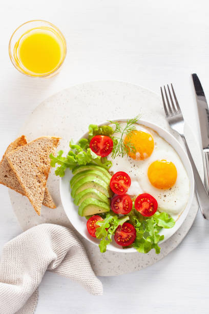 istock healthy breakfast flat lay. fried eggs, avocado, tomato, toasts 1047658360