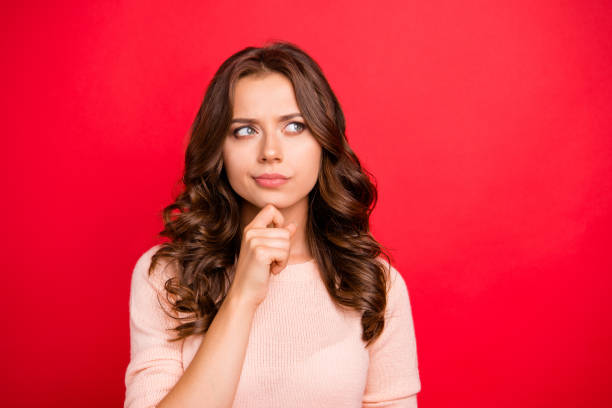 primo piano ritratto della signora pensante guardare da parte, toccare mano per mento stare in abito casual isolato su sfondo rosso brillante con spazio di copia per il testo - silence curly hair facial expression female foto e immagini stock