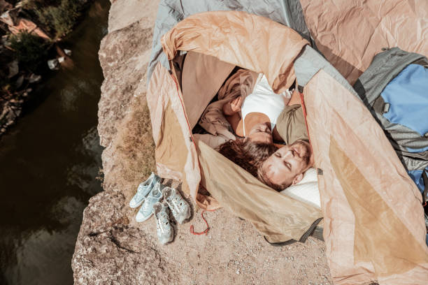 istock Dark-haired curly woman feeling rested while sleeping in tent with her boyfriend 1047658614