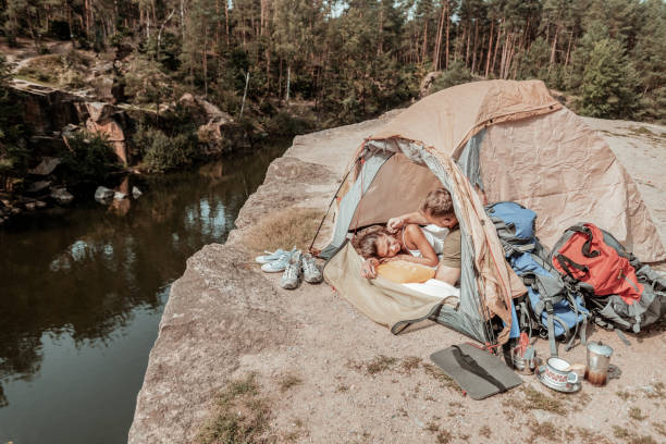 istock Caring blonde-haired man touching his beautiful girlfriend while lying in tent 1047658688
