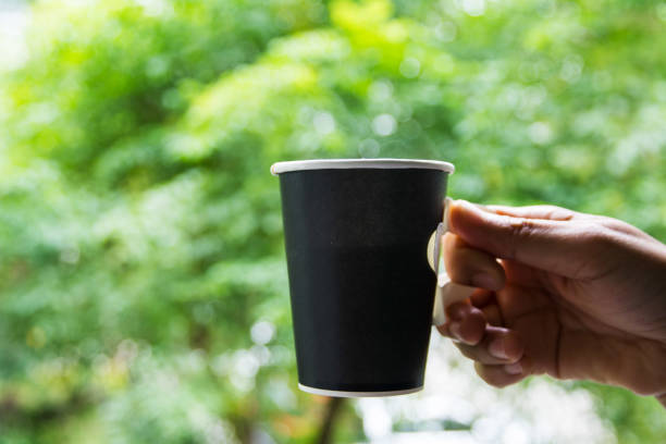 istock Black paper coffee cup in hand on green leave background 1047658702