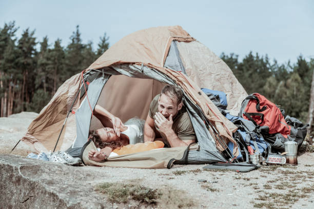 istock Two backpackers yawning together while waking up in their tent in forest 1047658712