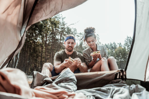 istock Caring loving girlfriend making some sandwiches with lettuce after waking in tent 1047658826