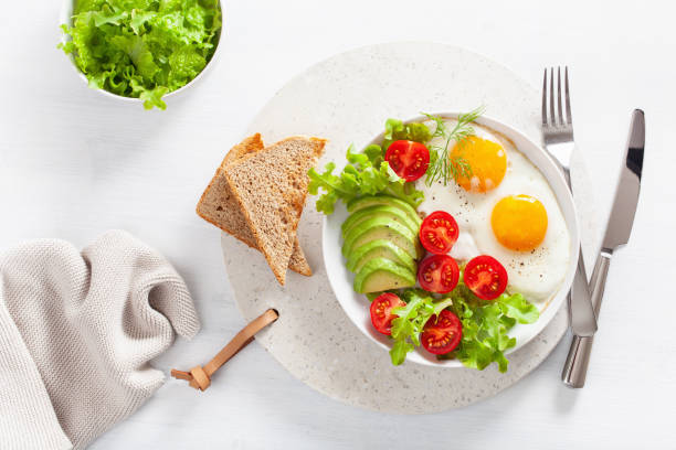 istock healthy breakfast flat lay. fried eggs, avocado, tomato, toasts 1047658844