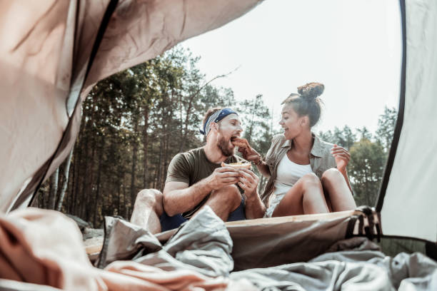 istock Dark-haired woman having fun while having breakfast with her man in tent camp 1047658854