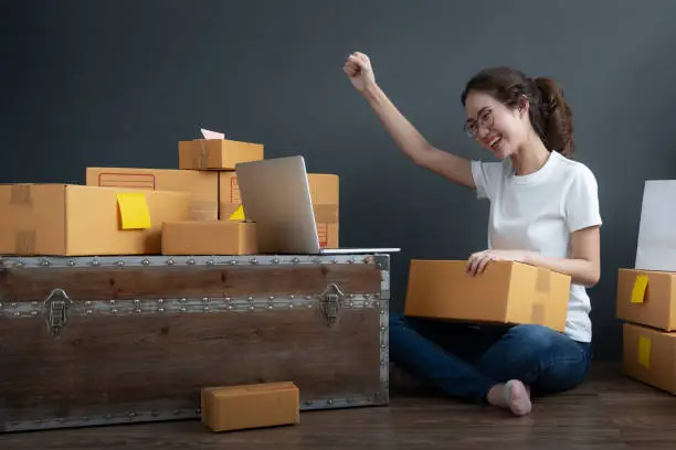 Photo of Young women happy after new order from customer, Business owner working at home office packaging on background. Online shopping SME entrepreneur or freelance working concept.