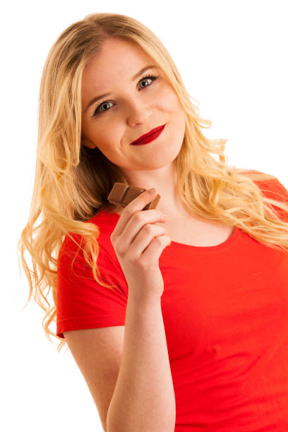 istock Cute young woman eating chocolate isolated over white background 1047665028