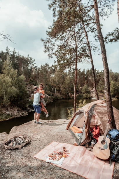 istock Strong handsome man lifting his appealing girlfriend standing near tent 1047669710