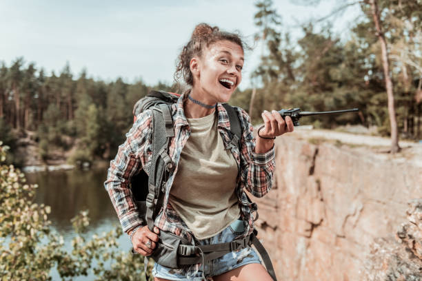istock Dark-haired female hiker wearing denim shorts and squared shirt using her pager 1047669810