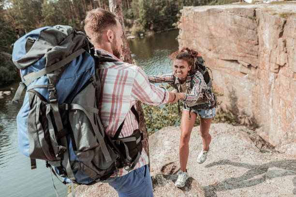 istock Curly dark-haired woman with heavy backpack feeling tired hiking with her man 1047670714