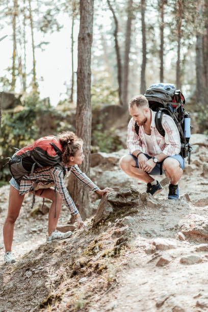 istock Dark-haired woman with heavy backpack talking to her boyfriend while hiking 1047672168