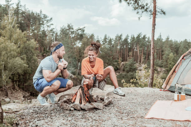 istock Beaming happy loving couple feeling funny while starting camp fire together 1047672412