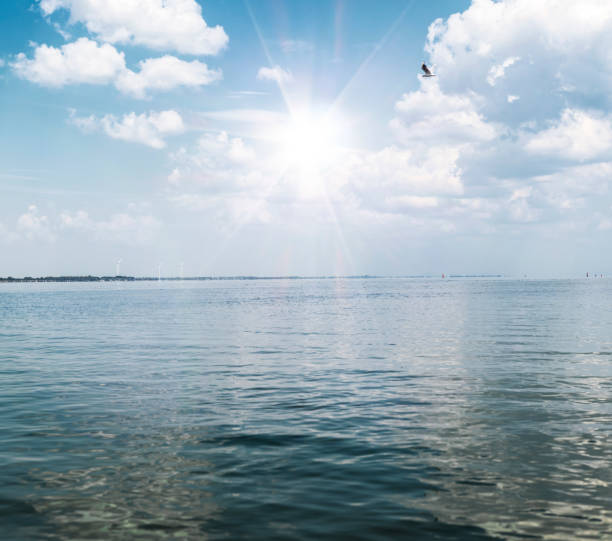 view of the sea with white fluffy clouds and a bright summer sun, the village of Lazurne Ukraine