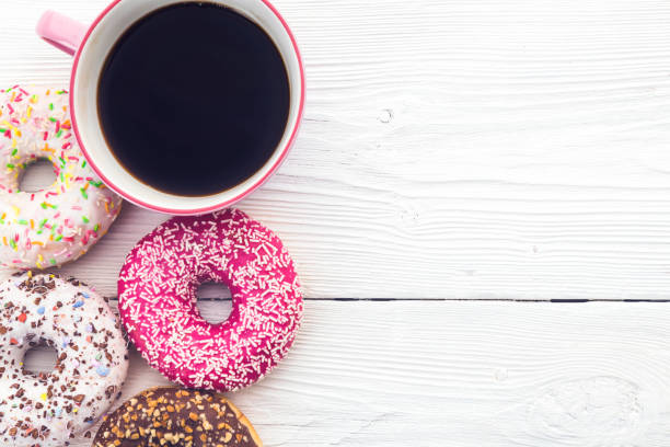 istock Coffee and donuts on wooden background 1047676690
