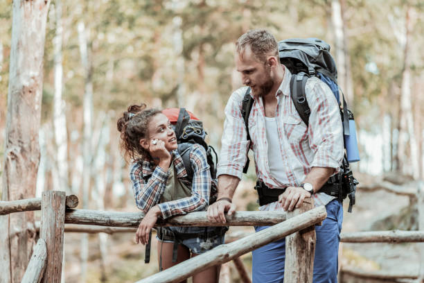 istock Couple of active backpackers standing somewhere in forest and talking 1047677076