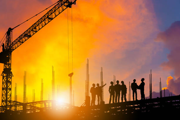 istock Silhouette of Engineer and worker on building site, construction site with clipping path at sunset in evening time. 1047680994