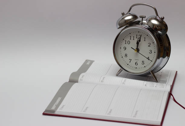 istock Notebooks and turquoise alarm clock on white wooden background 1047683694