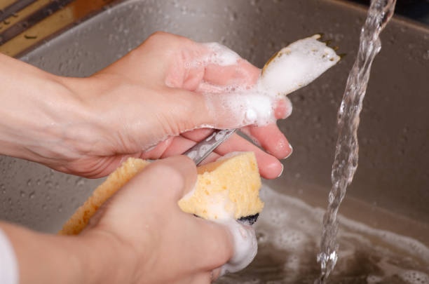 istock Sponge for washing utensils a spoon in the hands of a kitchen 1047683804