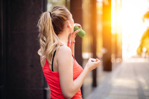 la giovane donna sta bevendo prima di allenarsi - smoothie fruit juice healthy eating foto e immagini stock