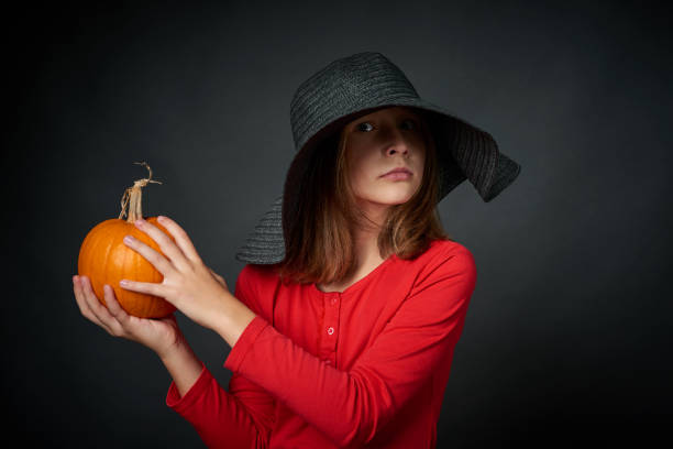 istock Angry girl in a black hat with pumpkin 1047684654