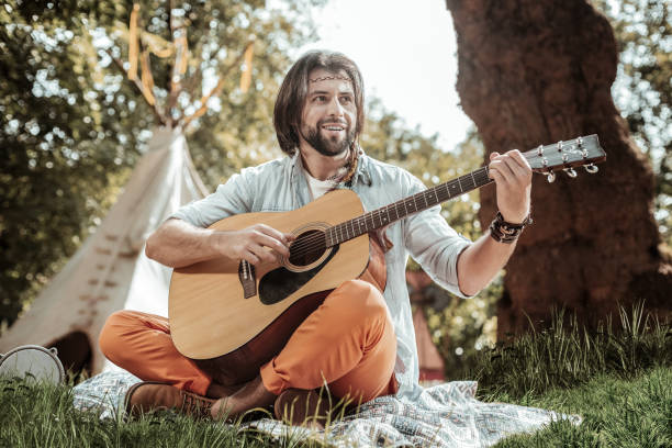 istock Pleasant man with guitar sitting on the grass 1047690626