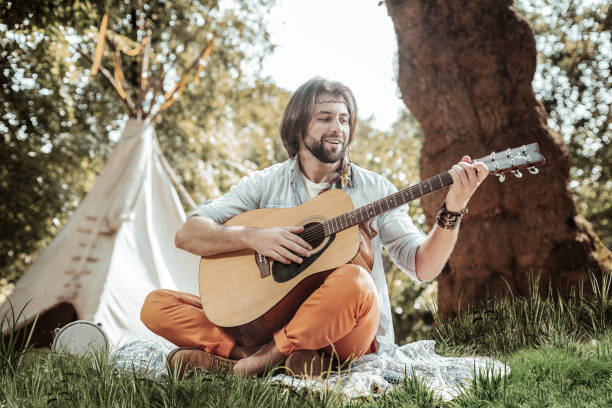 istock Handsome young man playing guitar near tent 1047690630