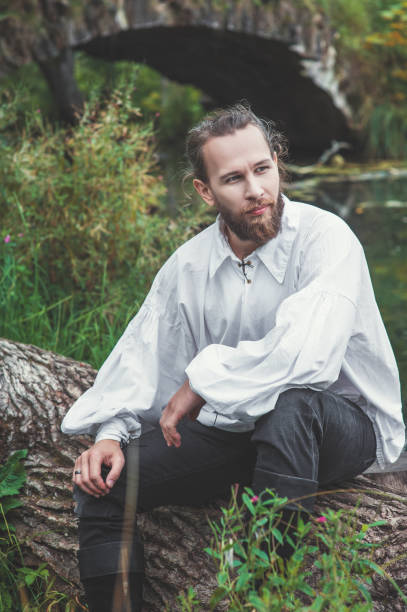 istock Handsome man in medieval costume sitting on the tree 1047693202